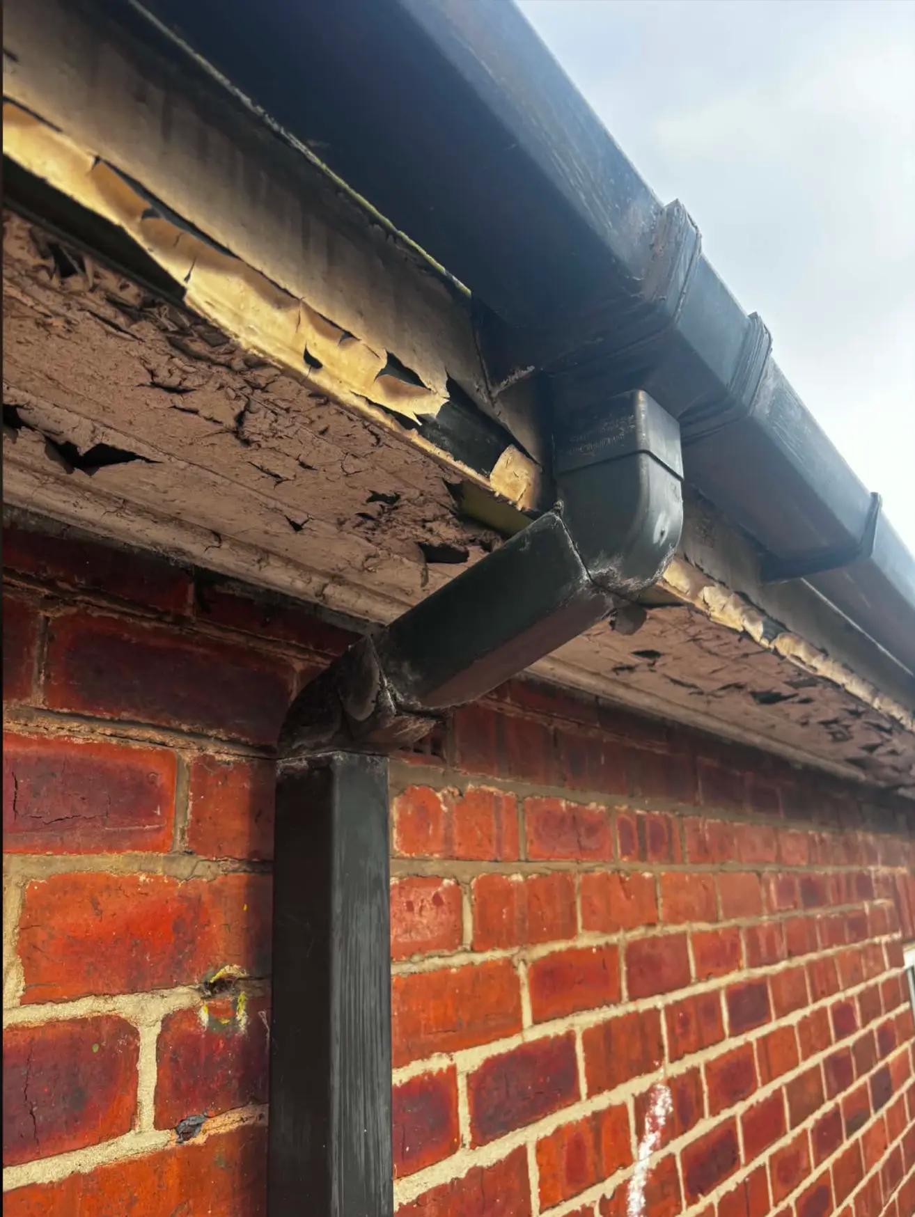 Damaged roofline and ageing downpipe before replacement work